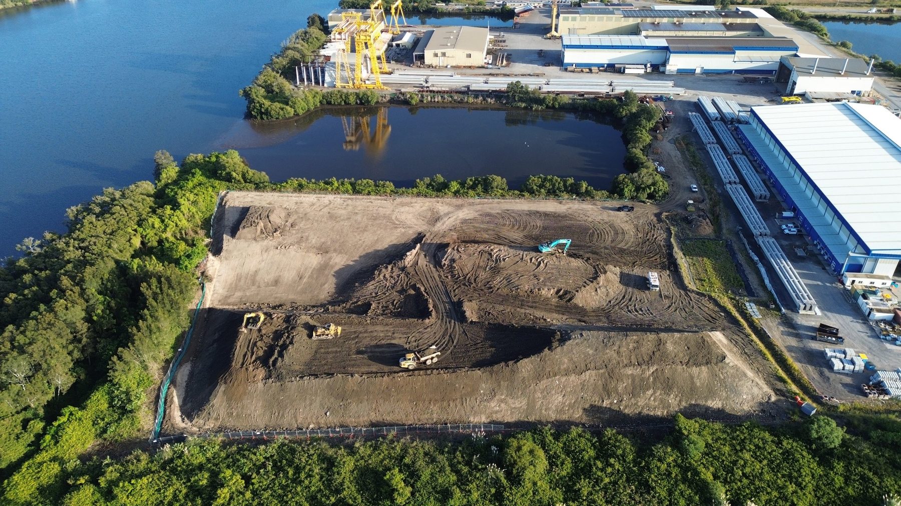 Aerial view of JSN Civil earthworks beside industrial buildings and water