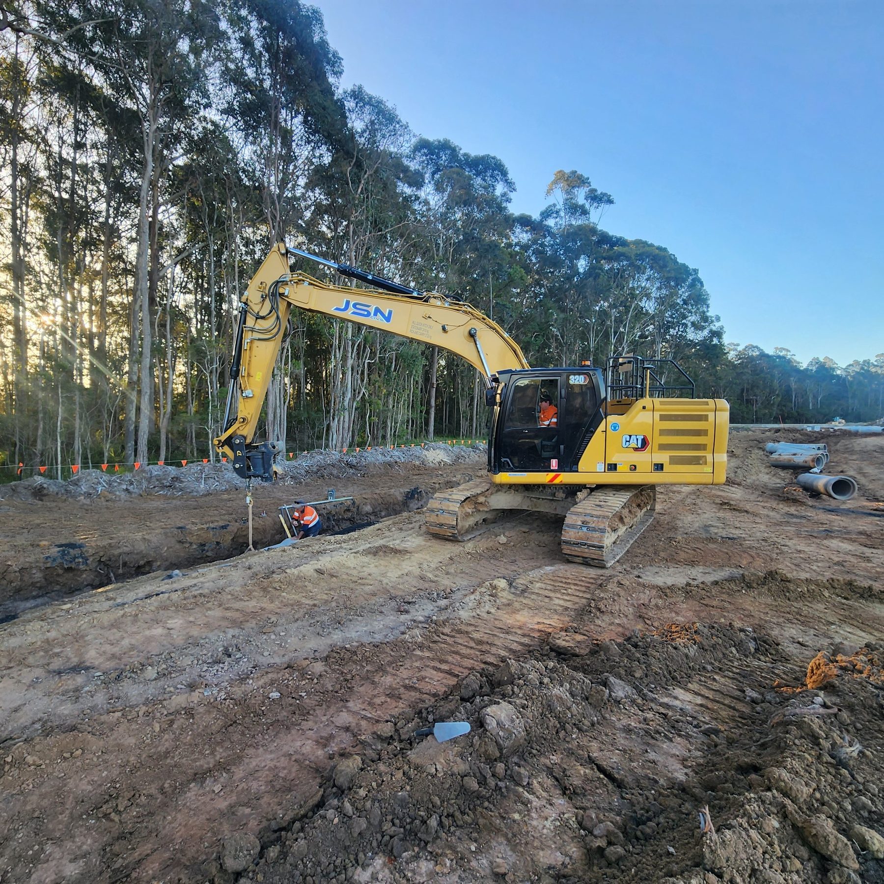 Excavator working beside a trench on a civil site